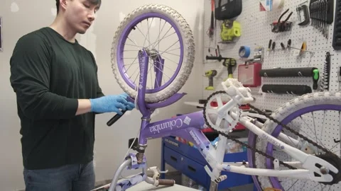 Asian man uses tools to fix wheel of a bike San Francisco CA USA July 15 2025 Stock Footage 313171571