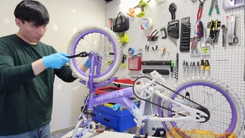 Asian man uses tools to fix wheel of a bike San Francisco CA USA July 15 2025 Stock Footage 313171616