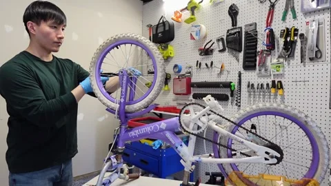 Asian man uses tools to fix wheel of a bike San Francisco CA USA July 15 2025 Stock Footage 313171619