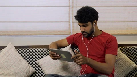 Asian man using digital tablet while sitting on couch at home. 스톡 동영상 155576620