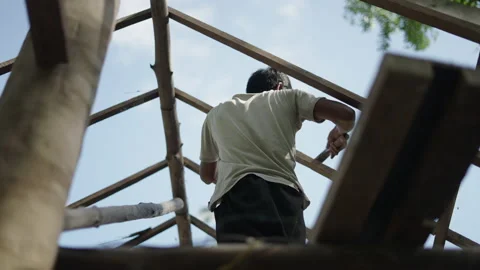 Asian man using a hammer to pin nails into a roof wood Stock Footage 232582132