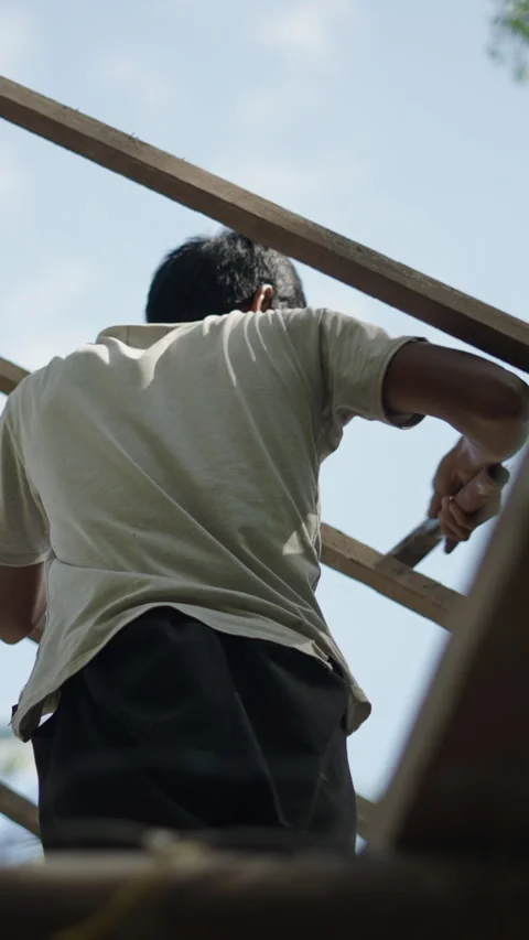 Asian man using a hammer to pin nails into a roof wood - FHD Vertical video Stock Footage 265479213