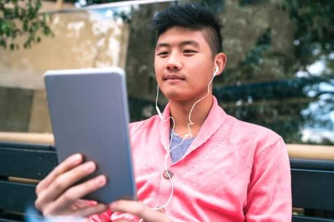 Asian man using his digital tablet with earphones. Stock Photos