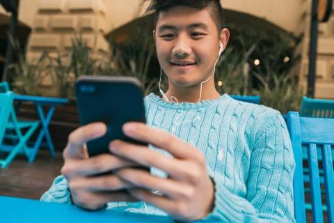 Asian man using his mobile phone with earphones. Stock Photos