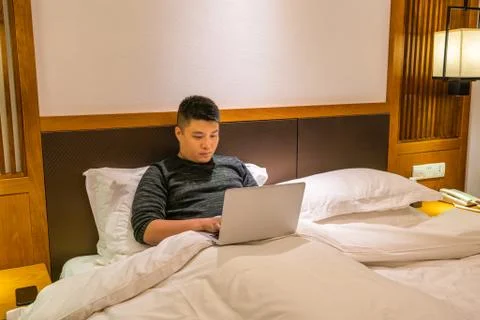 Asian man using laptop on the bed at night Stock Photos