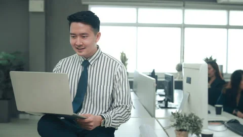An Asian man is using laptop computer , video calling to business partner in  Stock Footage 168116672