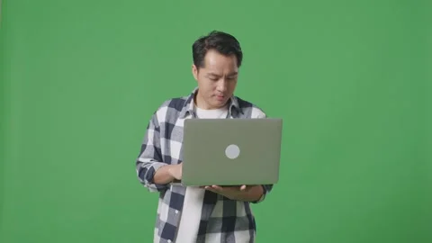 Asian Man Using Laptop Computer While Walking On The Green Screen Studio Stock Footage 248006195