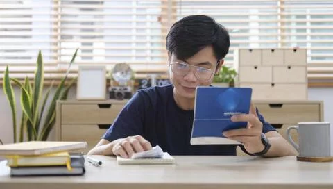 Asian man using laptop computer and counting taxes or house expenditures. Foto stock