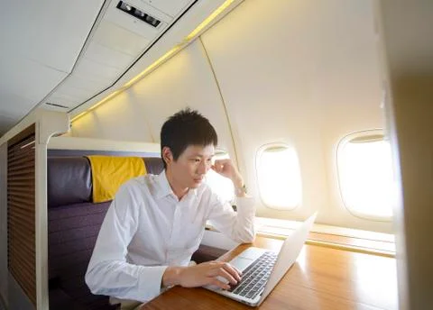 Asian man using laptop on first class airplane Stock Photos