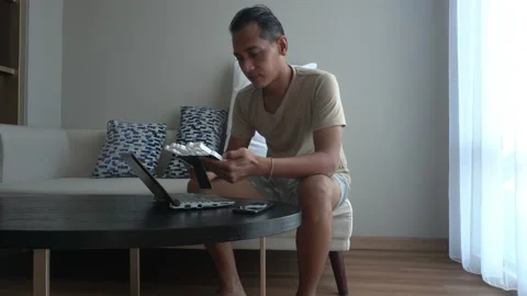 Asian man using laptop while Sitting in the coach of living room 스톡 동영상 226942245