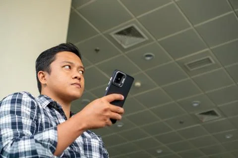 Asian man using mobile phone in airport waiting area. Male Tourist Sitting .. Stock Photos