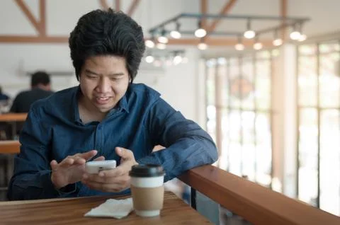 Asian man using phone in coffee shop Stock Photos