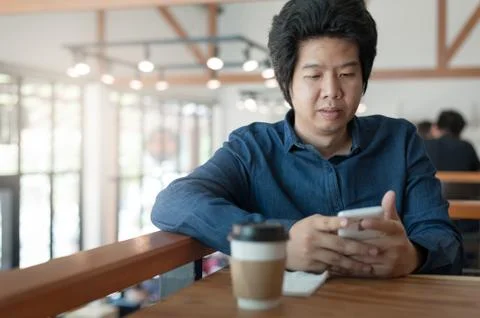 Asian man using phone in coffee shop Stock Photos
