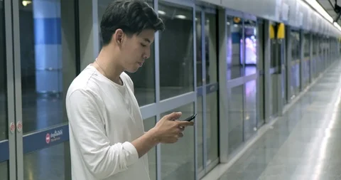 Asian man using smart phone and pointing while waiting for train in subway. Stock Footage 106384477