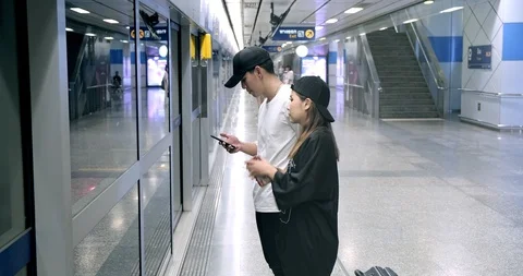 Asian man using smart phone while waiting for train in subway with his friend. Stock Footage 106384702