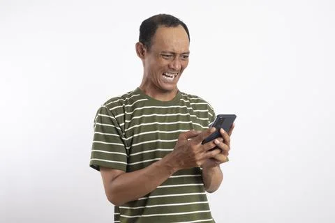 Asian man using smartphone with annoyed expression. Stock Photos