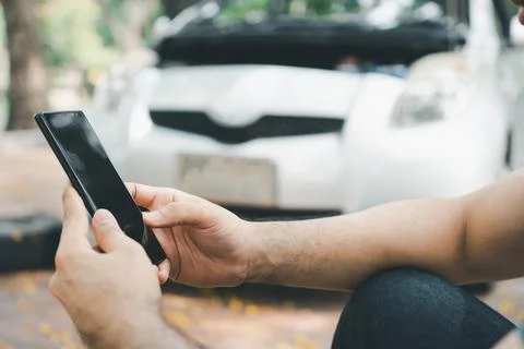 Asian man using smartphone for assistance after a car breakdown on street. Co Stock Photos
