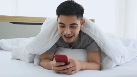 Asian man using a smartphone to chat and social networking in bedroom. Stock Footage 144087382