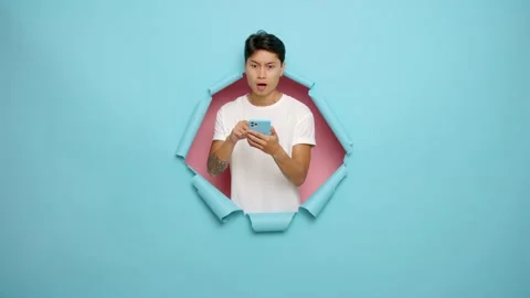 Asian man using a smartphone, distracted for a second to think, ponders 库存影片 231990728