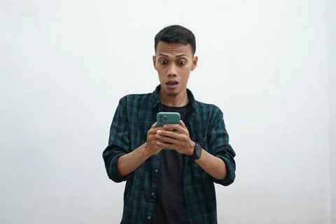 Asian man using smartphone. He looks at the phone and looks very surprised... Stock Photos