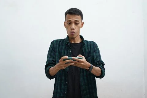 Asian man using smartphone. He looks at the phone and looks very surprised... Stock Photos