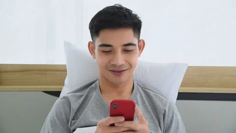 Asian man using smartphone to listening to music in bedroom Stock Footage 142554700