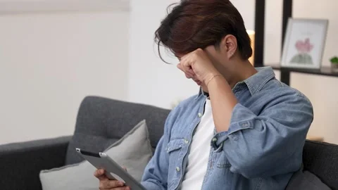 Asian Man Using Tablet Computer While Sitting on Living Room Couch Stock Footage 331561673