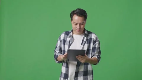 Asian Man Using Tablet While Walking On Green Screen In The Studio Stock Footage 248006095