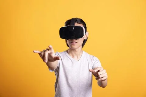Asian man using VR headset reaching hands in 3D simulation Stock Photos