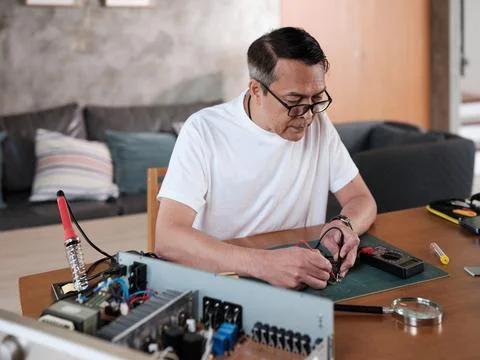 Asian man voltage test on electronics component circuit board with multimeter. 스톡 사진