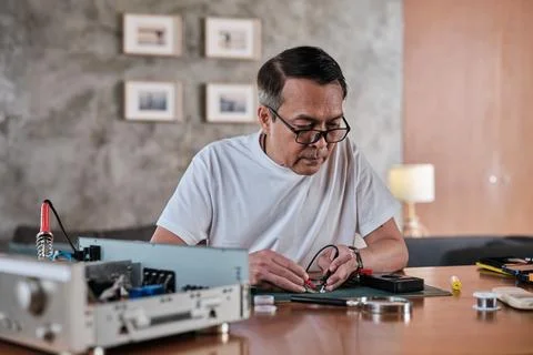 Asian man voltage test on electronics component circuit board with multimeter. 스톡 사진