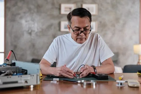 Asian man voltage test on electronics component circuit board with multimeter. 스톡 사진