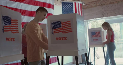 An Asian man voting along with two female voters, trees and flags in background Stock Footage 274918758