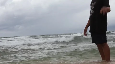 Asian man walking on the beach full of crashing ocean waves Stock Footage 297730967