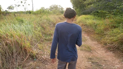 Asian man walking on the grass path, in the afternoon Stock Footage 126933370