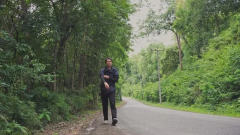 Asian man walking at side of road in tropical forest Stock Footage 250163127