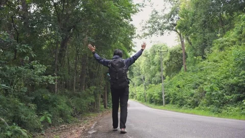 Asian man walking at side of road in tropical forest Stock Footage 250163128