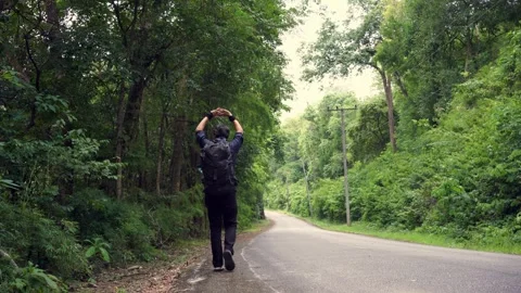Asian man walking at side of road in tropical forest Stock Footage 252425174