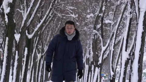 Asian man walking in a snowy path during winter time towards camera Stock Footage 146476901