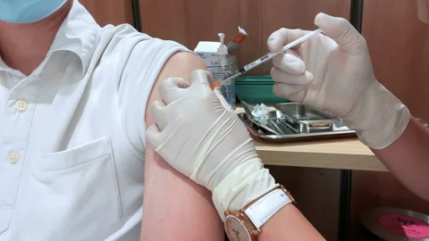 Asian man wear face mask receive Coronavirus vaccine injection jab Video stock 157021653
