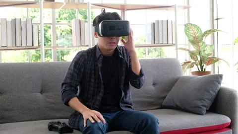 Asian man is wearing 3D virtual reality headset and is scared of something. Stock Footage 171257565