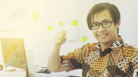 Asian Man Wearing Batik Drinks Coffee and Smiles to The Camera - Slow Motion Stock Footage 60615845