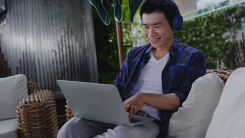 Asian man wearing headphone talking, greeting to video call with laptop meeting  Stock Footage 159750085