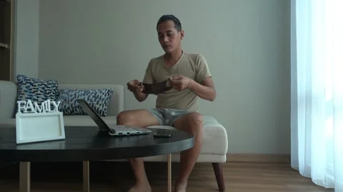 Asian man wearing mask while working from home. using laptop in the living room Stock Footage 226947620