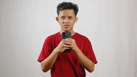 Asian man wearing red t-shirt holding smartphone recording voice Stock Footage 319923737