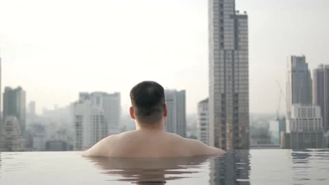 Asian man while relaxing when in infinite swimming pool with background of ci Stock Footage 167321338