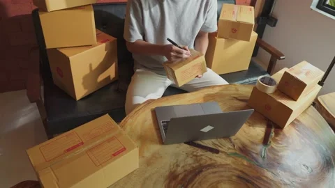 Asian man working laptop computer from home floor with postal parcel. Stock Footage 211562060