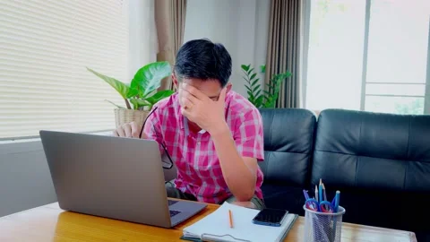 Asian man is working on a laptop device working from home. Are showing disappoin Stock Footage 148089480