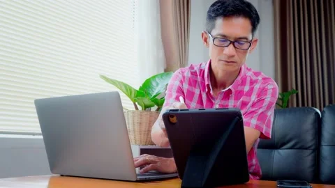 Asian man is working on a laptop device working from home. Are showing signs of  Stock Footage 148090626