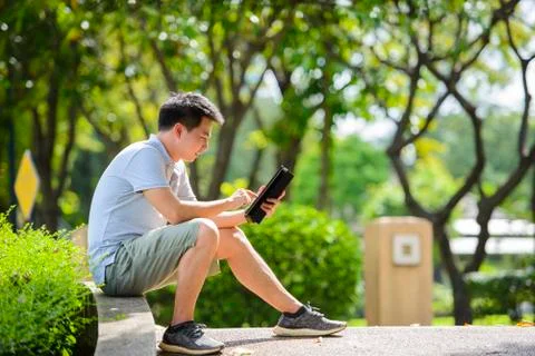 Asian man working with tablet computer outdoor in park Stock Photos